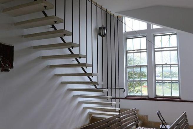 通往顶楼钟塔的「无扶手」楼梯，採穿透性设计，仅用 屋顶垂下的钢条、连结平面钢板镶入墙面，美不胜收。　图：参山国家风景区管理处／提供
