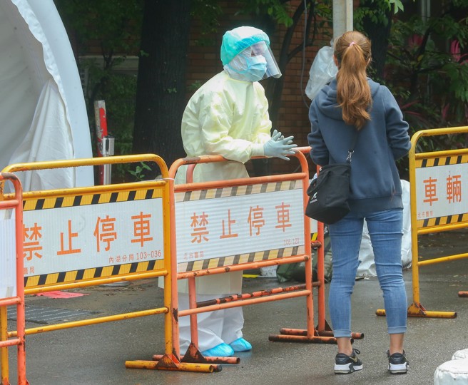 醫療應變組副組長羅一鈞預期，南部未來一周會有下降趨勢，後續還有待觀察。圖為醫護人員向民眾說明採檢流程。（資料照／粘耿豪攝）