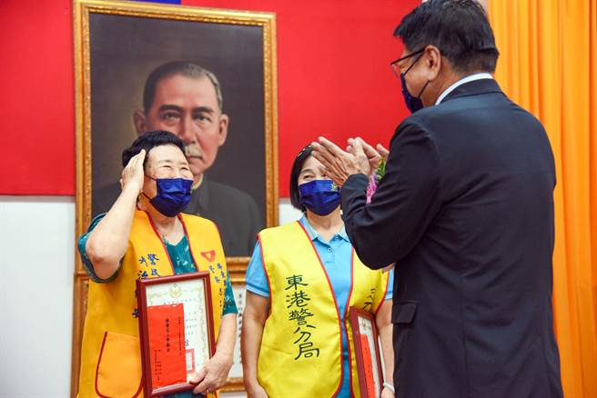 高龄81岁管云斌（左）获颁绩优警察志工，屏东县长潘孟安为她鼓掌。（屏警提供／林和生屏东传真）