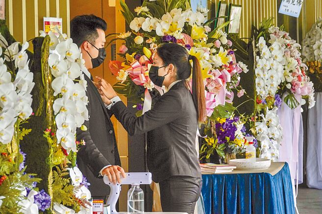 疫情指挥中心副指挥官陈宗彦指出，依据指引，遗体要「径送火化，尽速执行」，暂时不会更动火化的相关指引。图为礼仪公司人员正互相整理服装。（本报资料照片）