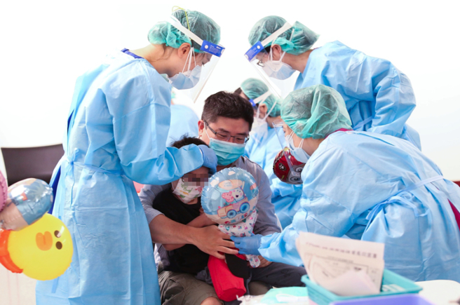 民眾帶小孩前往中正紀念堂接種疫苗，醫護送上氣球安撫。（資料照 陳俊吉攝）
