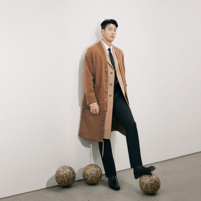 Burberry宣布英超職業足球運動員孫興慜擔任品牌大使，孫興慜以Burberry22早秋系列駝色外套大衣演繹正裝帥氣腳踩格紋足球拍攝畫報，讓不少粉絲敲碗品牌快上市該足球。（Burberry提供）