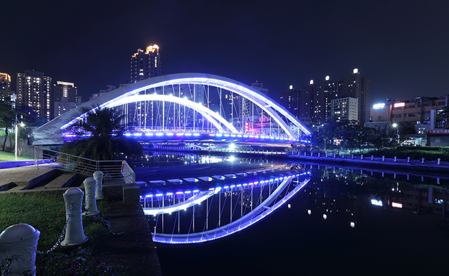 跨越愛河的願景橋位於中都濕地旁，夜晚打上藍色燈光，將河畔夜景點綴得浪漫夢幻。(攝影/Carter)