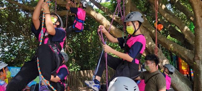  位于东海岸三仙台风景区的台东三仙国小16日举行毕业典礼，特别安排攀树成长礼课程，由教练带着毕业生环抱校园内「阿公级」的大榕树，表达感谢与亲近，接着毕业生代表抛绳、绑结，两人一组合作攀树，让毕业生各自从空中绳结取下自己的毕业证书。（图/ 中央社）