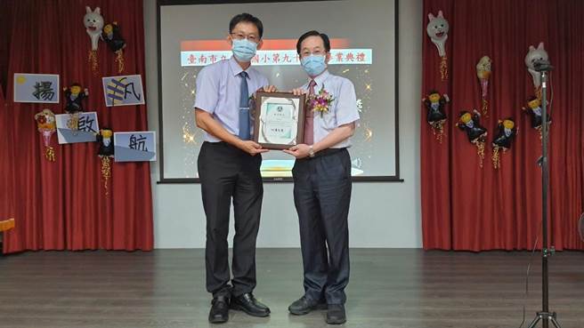 安业国小校长陈宏吉(左)为李良吉申请捐资教育事业银质奖牌感，由李良吉儿子李清吟代领。(台南市麻豆区安业国小提供／刘秀芬台南传真)
