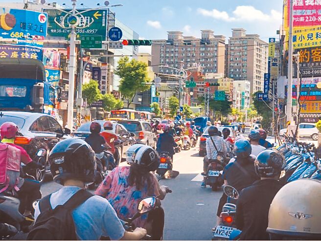 夏日炎炎，不少機車族停等紅燈時會躲在樹蔭下，台北市今年再祭夏日福音，6月15日至9月1日的上午9時至下午4時30分，全市770處路口將同步縮短紅燈秒數，平均達30秒。（本報資料照片）