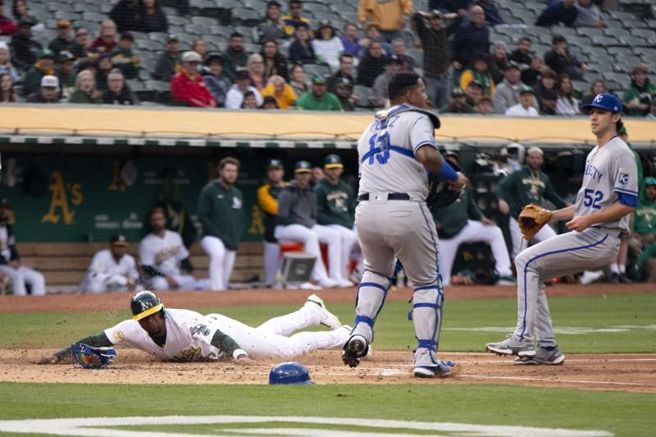 运动家安德鲁斯(左)趁着皇家投手暴投衝回本垒得分。（美联社）