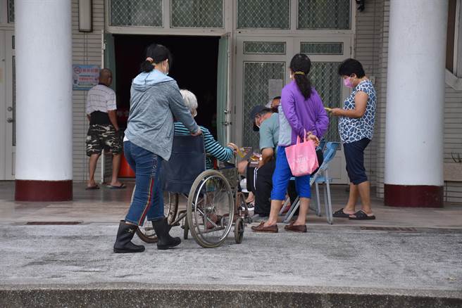 苗栗县政府18日在后龙镇维真国中开设大型接种站，一早就有长辈由照护工陪同赶往排队打苗。（谢明俊摄）