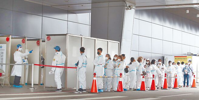 指挥中心17日公布，新增17例Omicron亚型变异株BA.4及BA.5境外移入病例。图为桃园机场第一航厦外的採检站，刚入境的外籍移工正在排队採检。（范扬光摄）