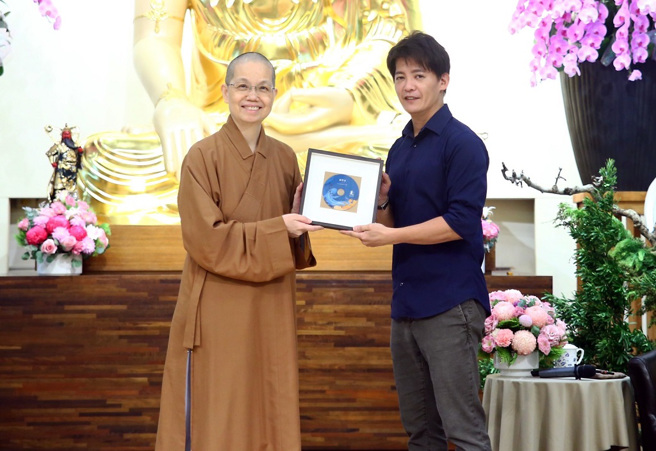 佛光山中區總住持覺居法師（左）致贈講座紀念光碟予講師謝哲青（右）。／佛光山惠中寺提供