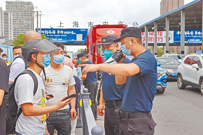 大陆近期多个城市调整入境隔离政策、呈现缩短天数趋势。图为昆山市花桥镇和上海市安亭镇之间公路检验站，工作人员20日向前往昆山的民眾解答防疫政策。（中新社）