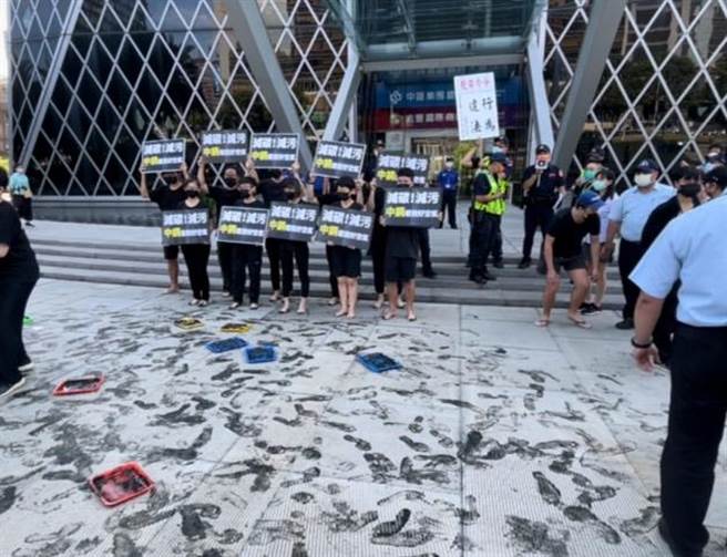 地球公民基金会22日到中钢集团总部大楼前展开抗议快闪行动，他们透过黑色顏料在大楼外围的地板留下满满「碳足迹」，诉求中钢在净零目标上有更进一步的作为。（洪浩轩摄）