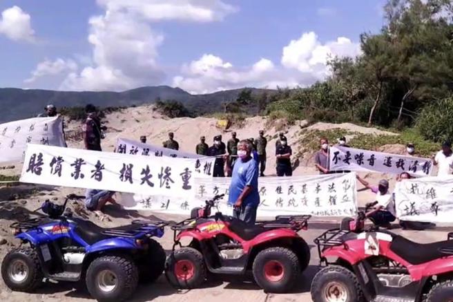 不满军方演训影响生计，屏东县满州乡居民高举「赔偿业者、损失惨重」与「不要噪音、还我清静」的白布条抗议。（图/ 中央社）