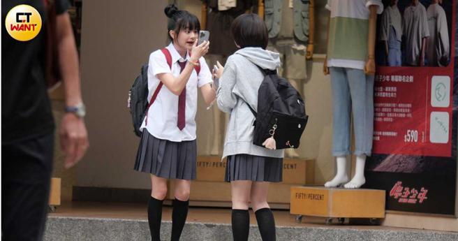 邵奕玫與身旁友人在街頭邊看手機邊笑鬧。（圖／本刊攝影組）