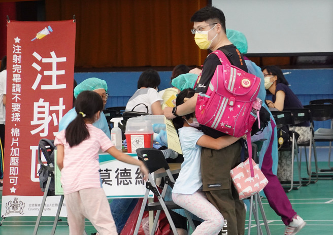 台北市兒童疫苗23日在校園開放接種，家長帶著孩子前往北市銘傳國小施打，小朋友雖有些害怕，但在大人懷抱下順利接種完畢。（姚志平攝）