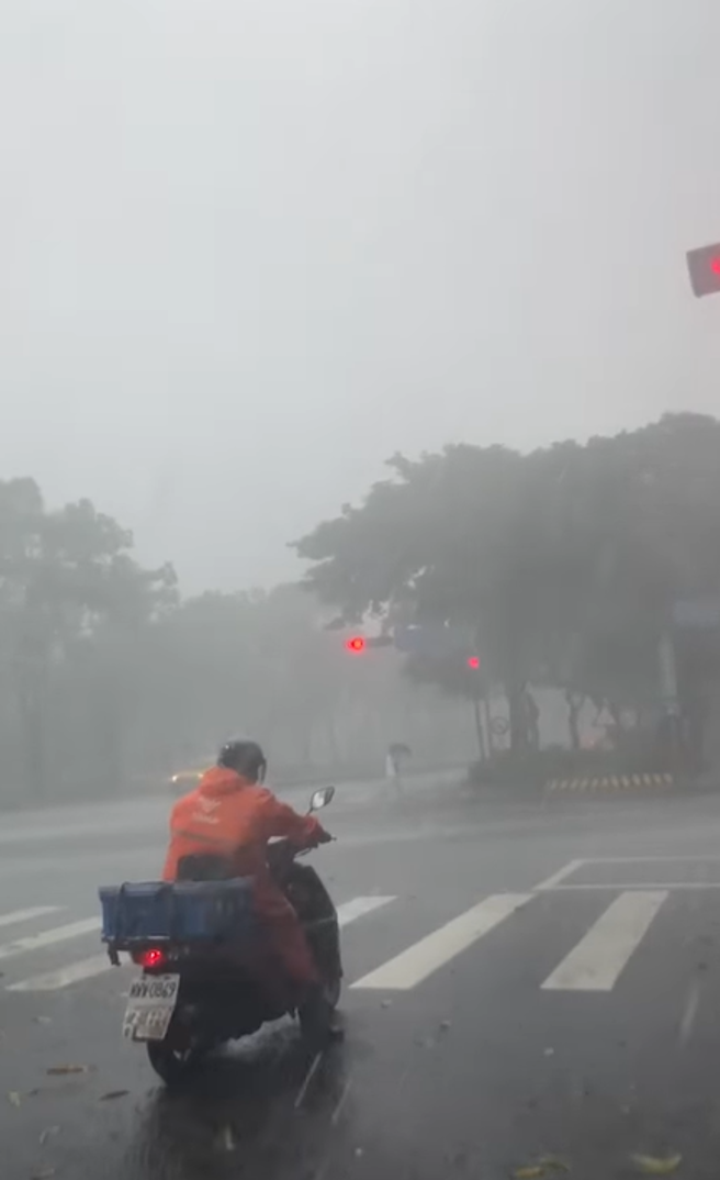 脸书上有网友分享1名外送员竟顶着恐怖风雨骑车跑单，在等红灯时被拍下，路面上全是遭砸落的树叶与瓜果，网友纷纷喊「先休息吧，安全第一呀」。（翻摄自脸书「外送员的奇闻怪事」）