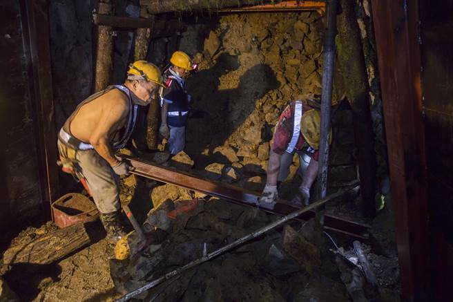 老矿工在坑道内顶着湿热环境，扛起大石块与钢梁依然游刃有余。（黄子明摄）