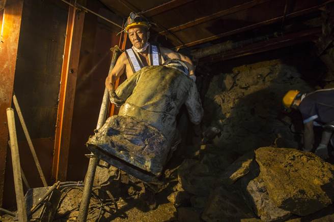 老矿工林启廷（中）在坑道内打赤膊工作，一把抓起矿工雕像搬离坑道，准备展开施工。（黄子明摄）