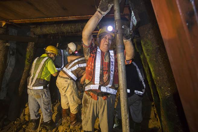 老矿工林松进（右一）用钢架撑住坑道顶部，准备更换坑壁钢梁。（黄子明摄）