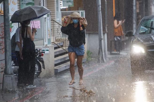 中央氣象局25日針對17縣市發布大雨特報，下午也針對台北市等8縣市發布大雷雨即時訊息，提醒民眾留意。圖為台北市中山商圈下午突然下起大雨，路上民眾措手不及，以衣服遮擋雨勢。（圖/ 中央社）