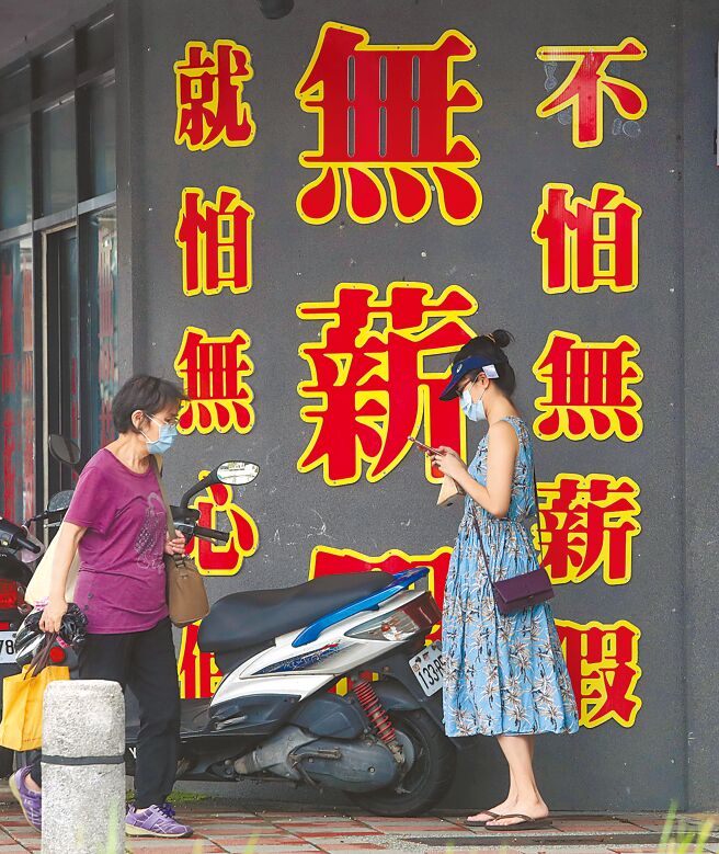 劳动部最新公布，本周实施无薪公司企业高达2912家、2万839人受影响，创下今年新高。图为民眾行经无薪假巨幅看板。（本报资料照片）