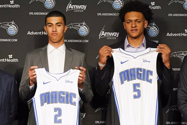 今年狀元班凱羅拿著魔術5號球衣亮相，左是今年第32順位新秀休斯坦。(美聯社資料照)