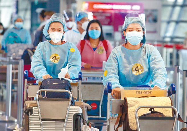 台湾防疫策略已走向共存，不论大人与儿童，接种疫苗，皆利大于弊。图为桃机入境大厅内身穿防护衣的旅客。（范扬光摄）