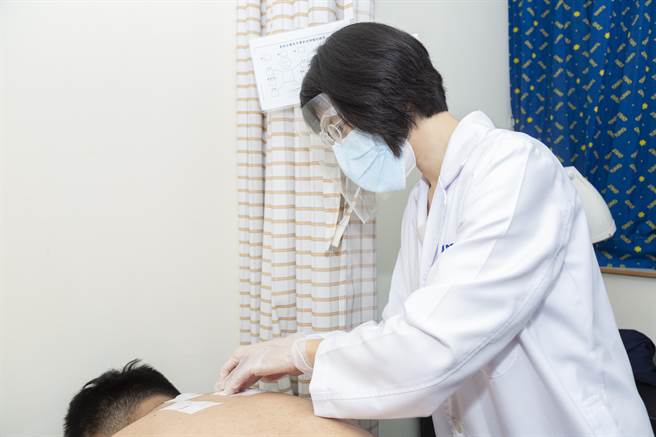 童综合医院中医部主任洪晨昕，将药饼敷贴在合适的穴位上。(童综合医院提供／陈世宗台中传真)