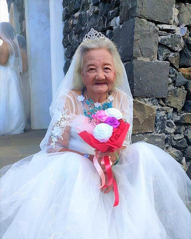 高齡92歲的何阿嬤家住澎湖七美西湖村，從沒穿過白色婚紗的她，拍照時笑得好開心。（呂汶駿提供）
