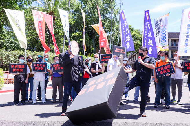 全國教師工會總聯合會30日在行政院門口舉牌抗議，要求軍公教員工待遇審議應制度化，並以行動劇方式，諷刺政府不在乎軍公教的薪資制度和生活尊嚴。（羅永銘攝）