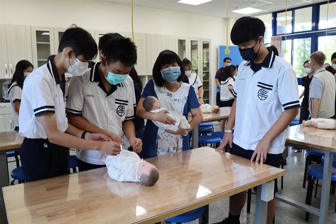 佳里国中校长李月华(右二)与学生体验为婴儿包尿布。(刘秀芬摄)