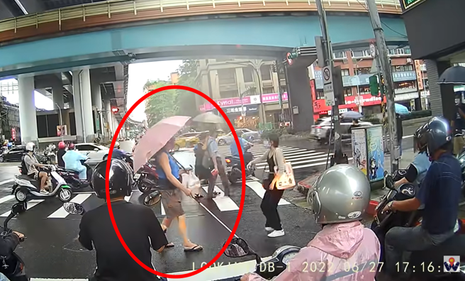 正妹过马路时发现后方有名视障人士也走在斑马线上，该名视障者逐渐走偏方向，朝车阵走去，该正妹因此走回路中牵着视障者的手指引方向。（翻摄自YouTube）