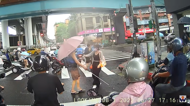 正妹过马路时发现后方有名视障人士也走在斑马线上，该名视障者逐渐走偏方向，朝车阵走去，该正妹因此走回路中牵着视障者的手指引方向。（翻摄自YouTube）