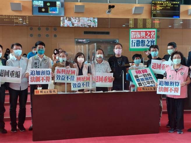 绿营高举标语牌痛批市府选前追加预算大撒币，变相以现金换选票，振兴经济沦为选举操作要求退回重编。（谢琼云摄）