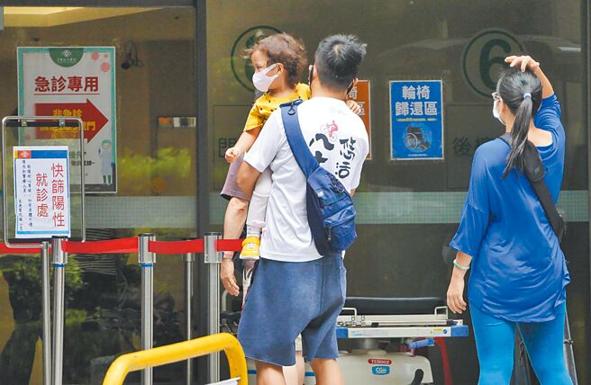 国内疫情有趋缓迹象，中央流行疫情指挥中心发言人庄人祥说，本土疫情要降到单日1万例以下「恐怕没那么快」，目前看来可能要等到7月底。3日医院的防疫急门诊外，家长抱着小孩前来看诊。（陈俊吉摄）