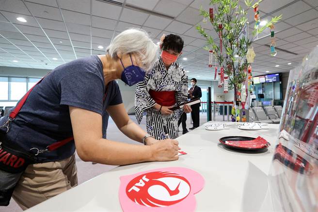 日本航空公司7日在桃机登机门举行七夕祈福活动，邀请搭机乘客在许愿福籤写下心愿。（陈麒全摄）