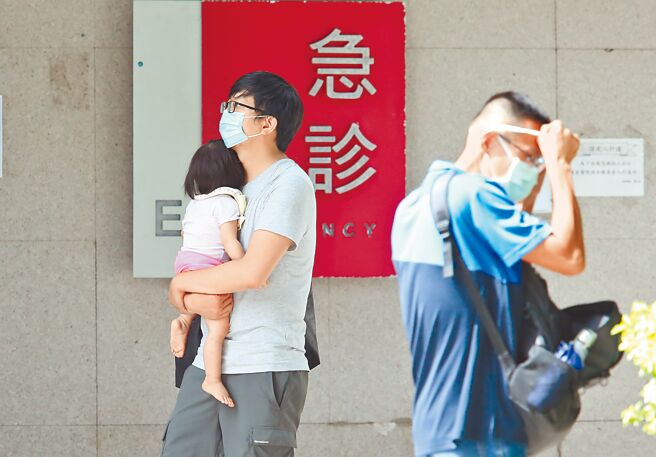 国内疫情有趋缓迹象，但专家建议尽量让孩子在今年接种流感疫苗。图为6日医院防疫急门诊外，家长抱着小孩前来看诊。（陈俊吉摄）