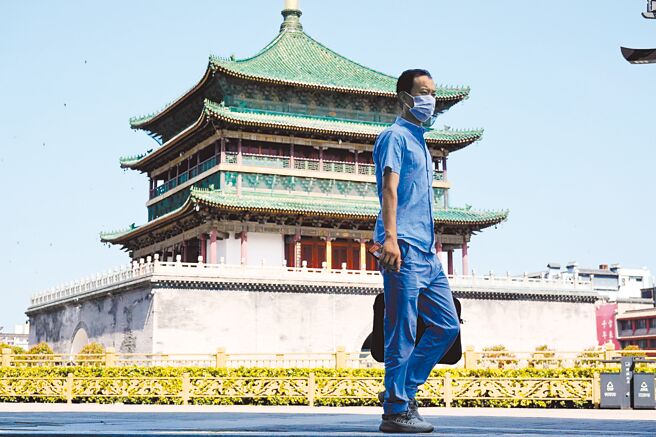 7月6日，陝西西安，一位市民從鐘樓前走過。當日0時起，西安全市實行7天臨時性管控措施。公眾娛樂休閑場所、公共文化活動場所等暫停營業1周。（中新社）