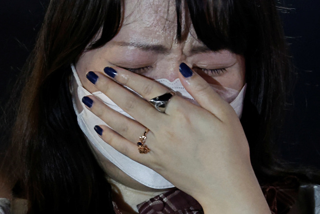 一名妇女在安倍枪击案发现场掩面痛哭。图非当事妈妈。（图／路透社）