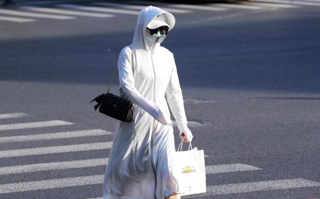 大陆各地高温肆虐，11省市有多地高温达37~39℃，10余城市超过40℃。图为上海40℃高温，民眾全身严密包覆防晒。（图／中新社）