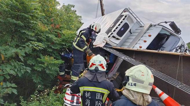 大貨車翻覆於外側車道壓住工程車頭，陳姓父子受困。（翻攝畫面／蔡明亘桃園傳真）