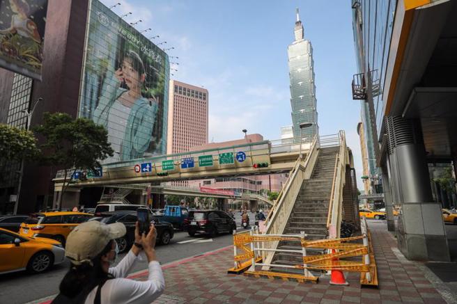位於台北市信義區信義路與基隆路交叉口的世貿人行天橋將退役，台北市新工處12日上午將天橋封閉，預計15日起利用連續2個週末晚間至週日凌晨分批拆除，路過民眾在天橋下拍照留念。（圖/ 中央社）
