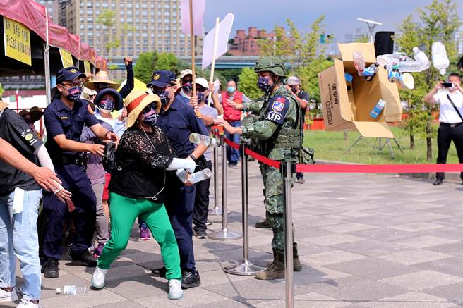 「全民防卫动员暨灾害防救（民安8号）演习」14日在新北市泰山塭仔圳重划区举行，实兵演练模拟大台北地区遭地震、豪雨及共军导弹袭击，现场灾民排队领取物资时，有不满的民眾闹场并丢掷物品，遭军警强制带离，演练过程逼真。（黄世麒摄）