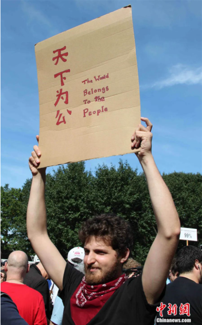 2011年，「佔領華爾街」示威者高舉「天下為公」標語。（中新社）