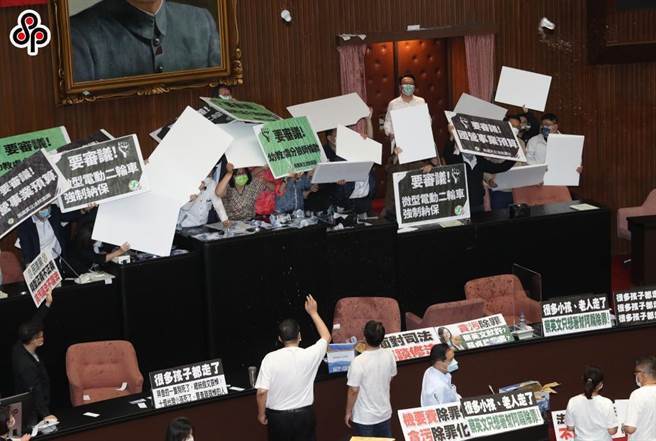 立法院院会处理攸关国务机要费除罪化的会计法第99条之一条文修正草案，不满民进党团要强行表决通过，国民党立委们丢杯水到主席台表达抗议，而在台上的民进党立委们则用纸板抵御杯水攻击。（刘宗龙摄）本报资料照片