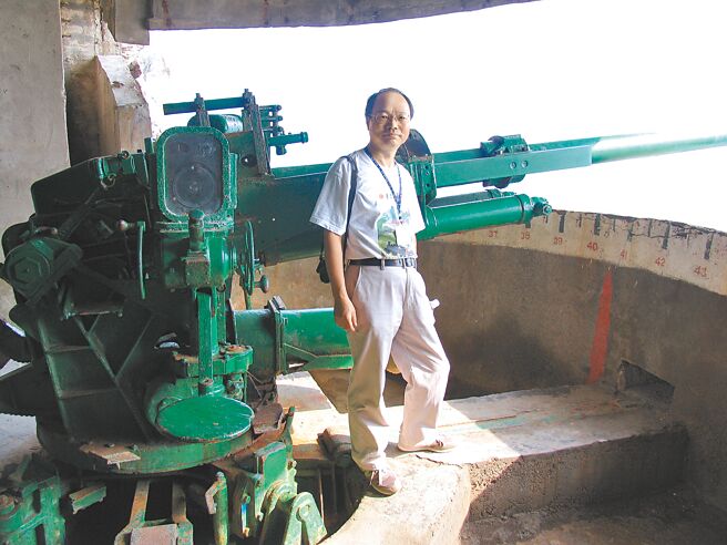 吳敏顯寫家鄉宜蘭，多篇文章收錄於港、台教科書。圖為他與龜山島碉堡裡的大砲合影。（吳敏顯提供）