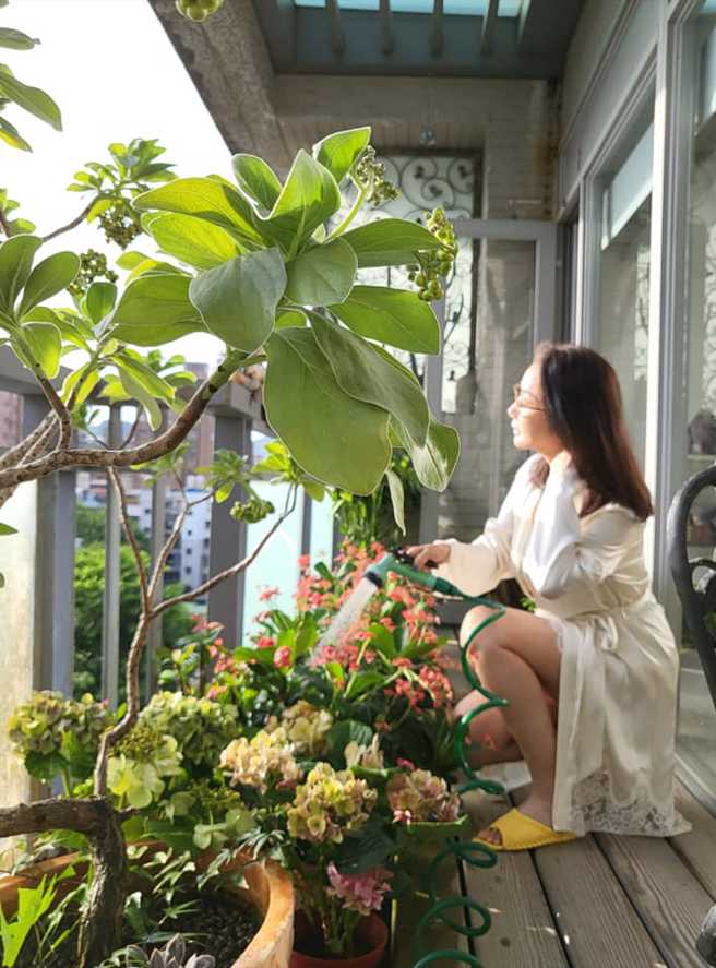 陳美鳳坐在陽台澆花曬太陽，白睡袍露出驚人大長腿。(圖/陳美鳳 FB)
