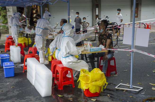 大陆各地受热浪侵袭，执行疫情防控的工作人员仍穿着全身式防护服，还得用冰块在现场降温。上海华山医院张文宏医师团队称，工作人员只要「一级+」的防护措施应该就能足以防止被感染，没有必要在酷热下穿着全身不通风的防护服。（图／新华社）