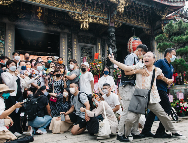 台北市长参选人陈时中20日前往龙山寺参拜，龙山寺董事长黄书玮赠送「以民为先」字画，有民眾（右）在媒体联访时接近陈大声呛声大喊「陈时中可以保障台北市民吗？」，随即遭维安人员架离现场。（资料照/郭吉铨摄）
