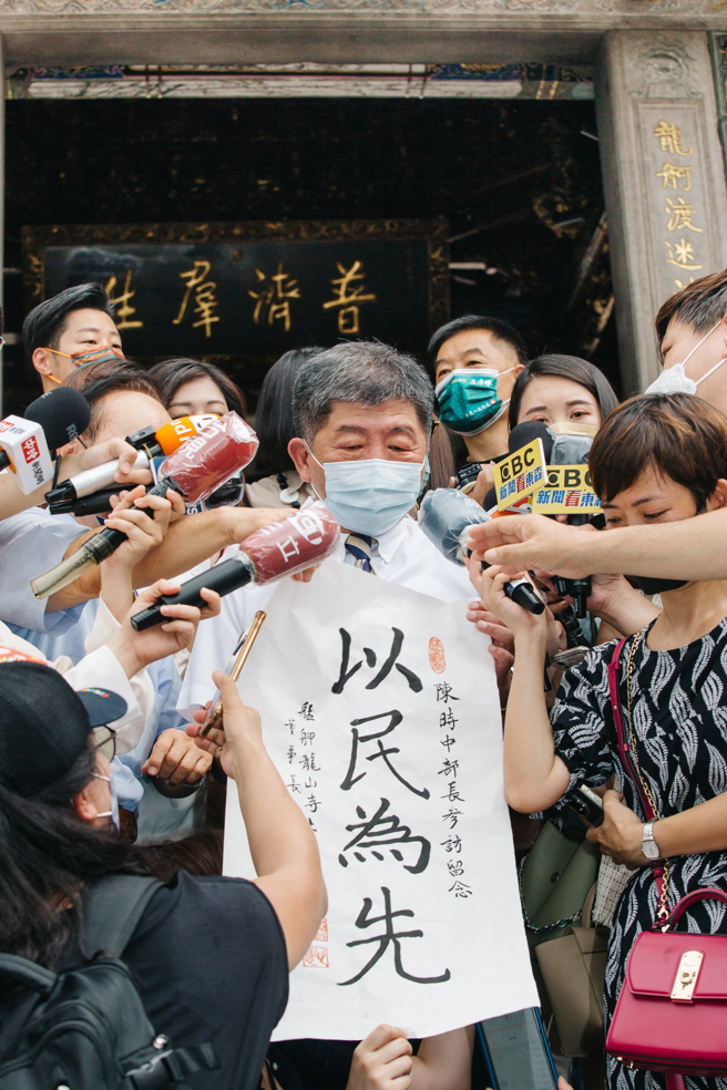 台北市长参选人陈时中(中)20日前往龙山寺参拜，龙山寺董事长黄书玮（中左）赠送「以民为先」字画。（资料照/郭吉铨摄）
